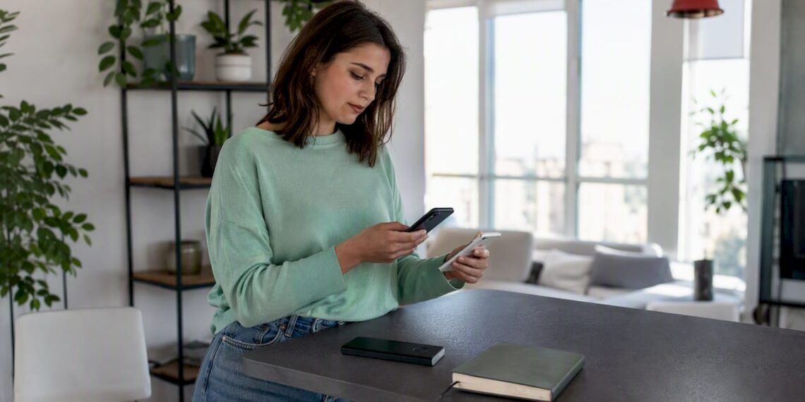 Eine Frau überträgt zu Hause ihre Daten von einem Android-Smartphone auf ein iPhone.