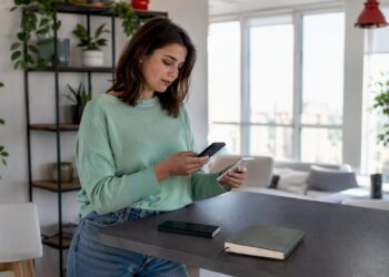 Eine Frau überträgt zu Hause ihre Daten von einem Android-Smartphone auf ein iPhone.