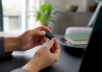 Jemand hält einen Bluetooth-Adapter in der Hand und steckt ihn gerade in den PC.