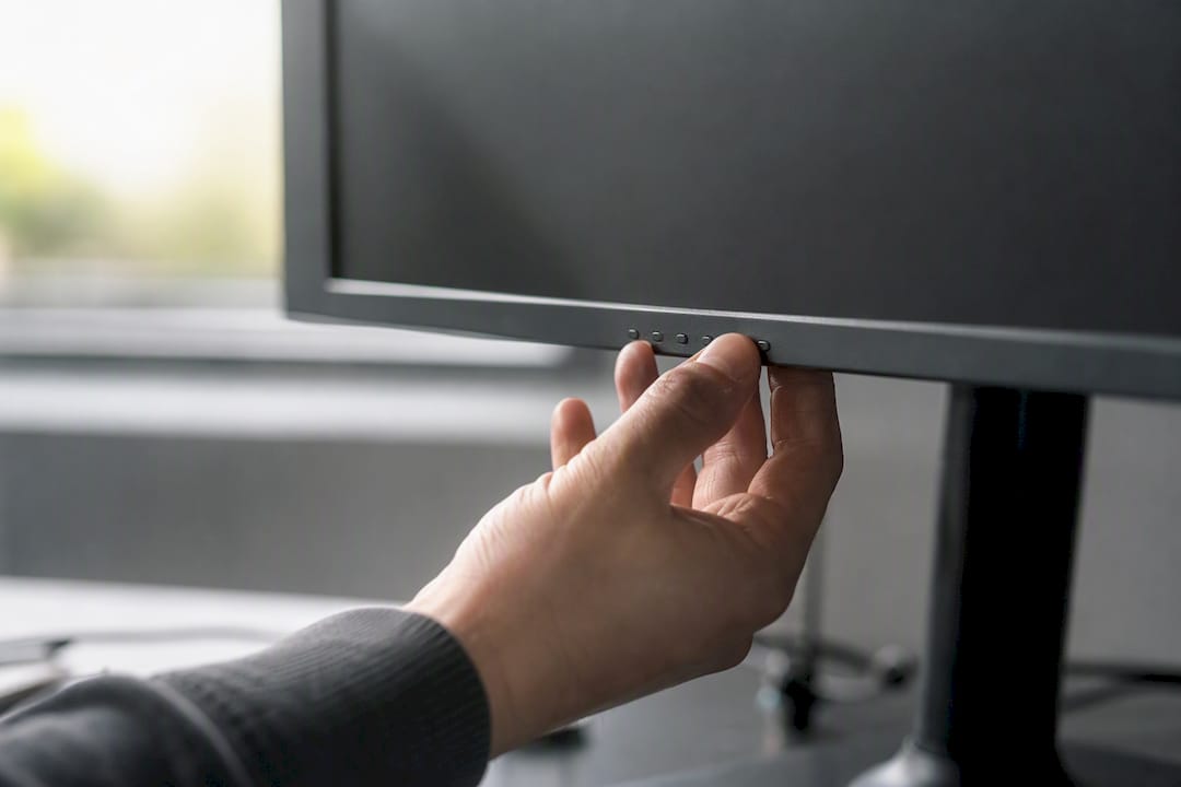 Hände justieren die Einstellungen am Monitor