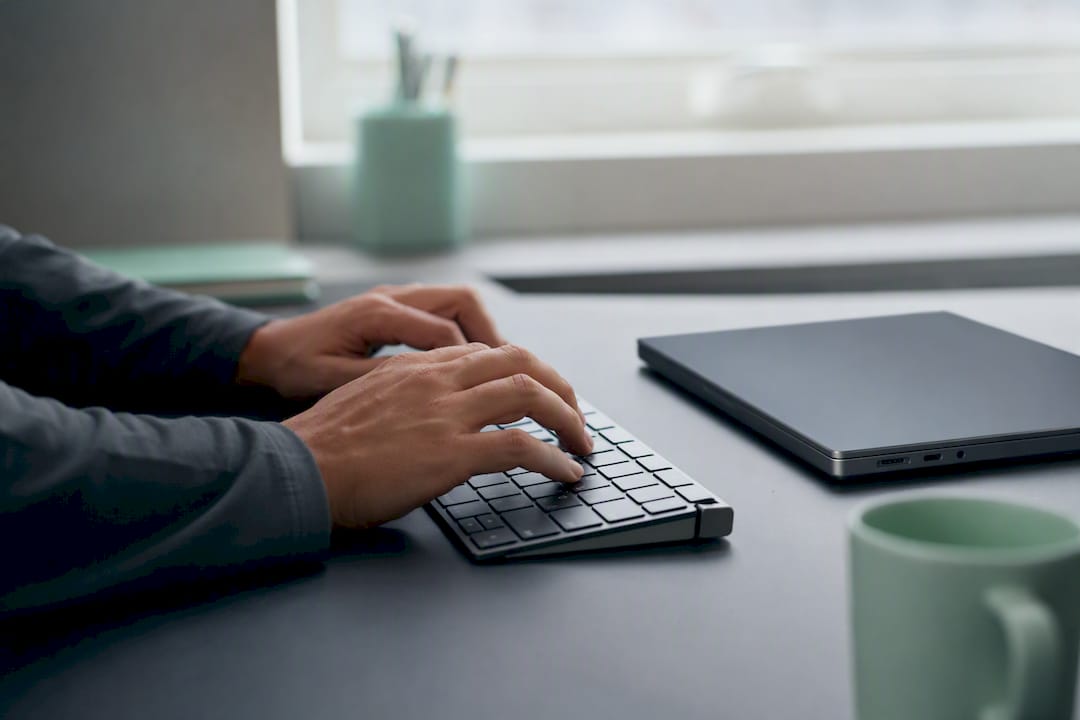 Eine Hand bedient die Maus direkt neben dem Laptop.
