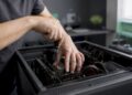 Jemand arbeitet mit den Händen am geöffneten PC-Gehäuse und repariert die Hardware.