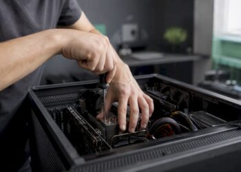 Jemand arbeitet mit den Händen am geöffneten PC-Gehäuse und repariert die Hardware.