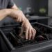 Jemand arbeitet mit den Händen am geöffneten PC-Gehäuse und repariert die Hardware.
