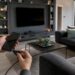 Hände verbinden Smartphone mit dem Fernseher per Kabel