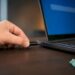 Hand hält USB-Stick neben gesperrtem Laptop