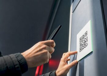 Hand scannt QR-Code auf einem öffentlichen Aushang