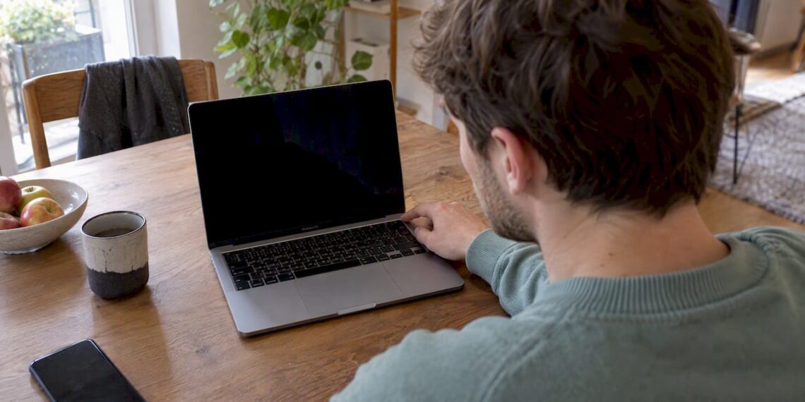 Person untersucht ein MacBook mit schwarzem Bildschirm
