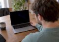 Person untersucht ein MacBook mit schwarzem Bildschirm